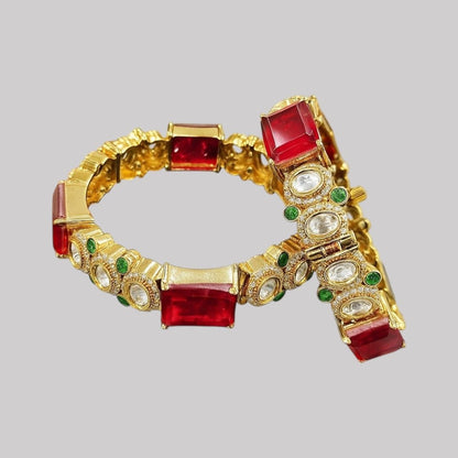 Gold - Plated Red Stone Bangles with Kundan & Green Detailing - Auraa Trends - Bangles -  - Auraa Trends - “Gold - plated traditional bangles with large red stones, kundan detailing, and green enamel accents – set of 2 displayed on white background with flowers.”