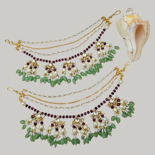 Green & Maroon Kundan Pearl Multi - Layer Kaan Chain - Auraa Trends - Kaan chain -  - Auraa Trends - Traditional multi - layer Kundan Pearl Kaan Chain with maroon beads, green drop beads, floral motifs, and pearl clusters, displayed on a soft fabric background with decorative flowers and a seashell.