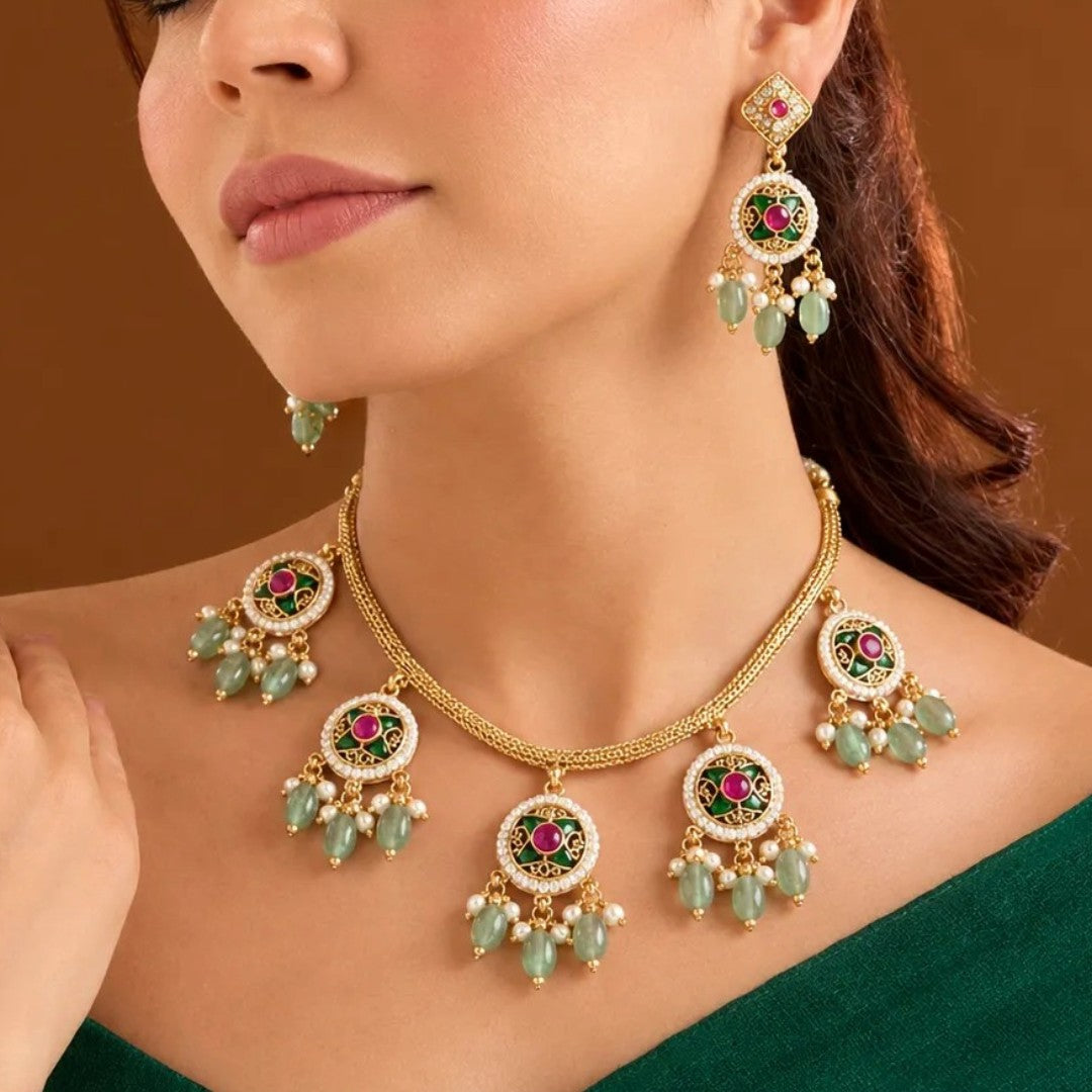 Antique gold plated choker necklace set with ruby pink medallions, mint green bead and pearl drops and matching earrings on a blue bust