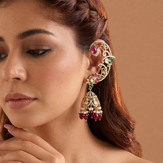 Gold plated ruby maroon ear cuff peacock jhumka earrings with American diamond stones, maroon beads and pearl hangings on a white background