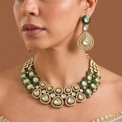 Gold-tone emerald green kundan choker necklace set with zircon halo medallions, pear-shaped clear stones and matching pear drop earrings on dark green velvet