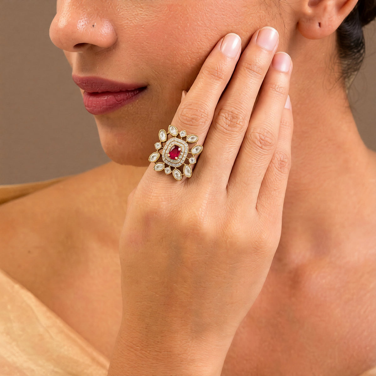 Gold-finish floral cocktail ring with a ruby-pink oval centre stone, double American diamond halo, and clear marquise-cut petal stones