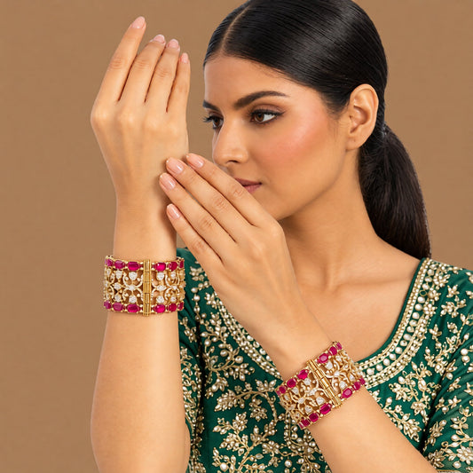 Pair of antique gold-finish wide kada bangles with ruby-pink rectangular stones, polki-style clear stones, and Victorian-style American diamond scrollwork