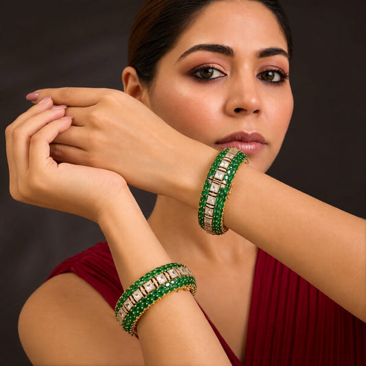 Pair of gold-finish openable kada bangles with emerald-green oval stones, a centre row of polki-style clear square stones, and American diamond detailing