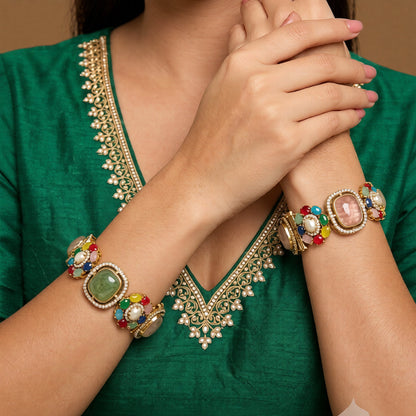 Pair of gold-finish openable kada bangles with pink and green cushion-cut stones, multicolour floral motifs, pearl-style centres, and American diamond frames
