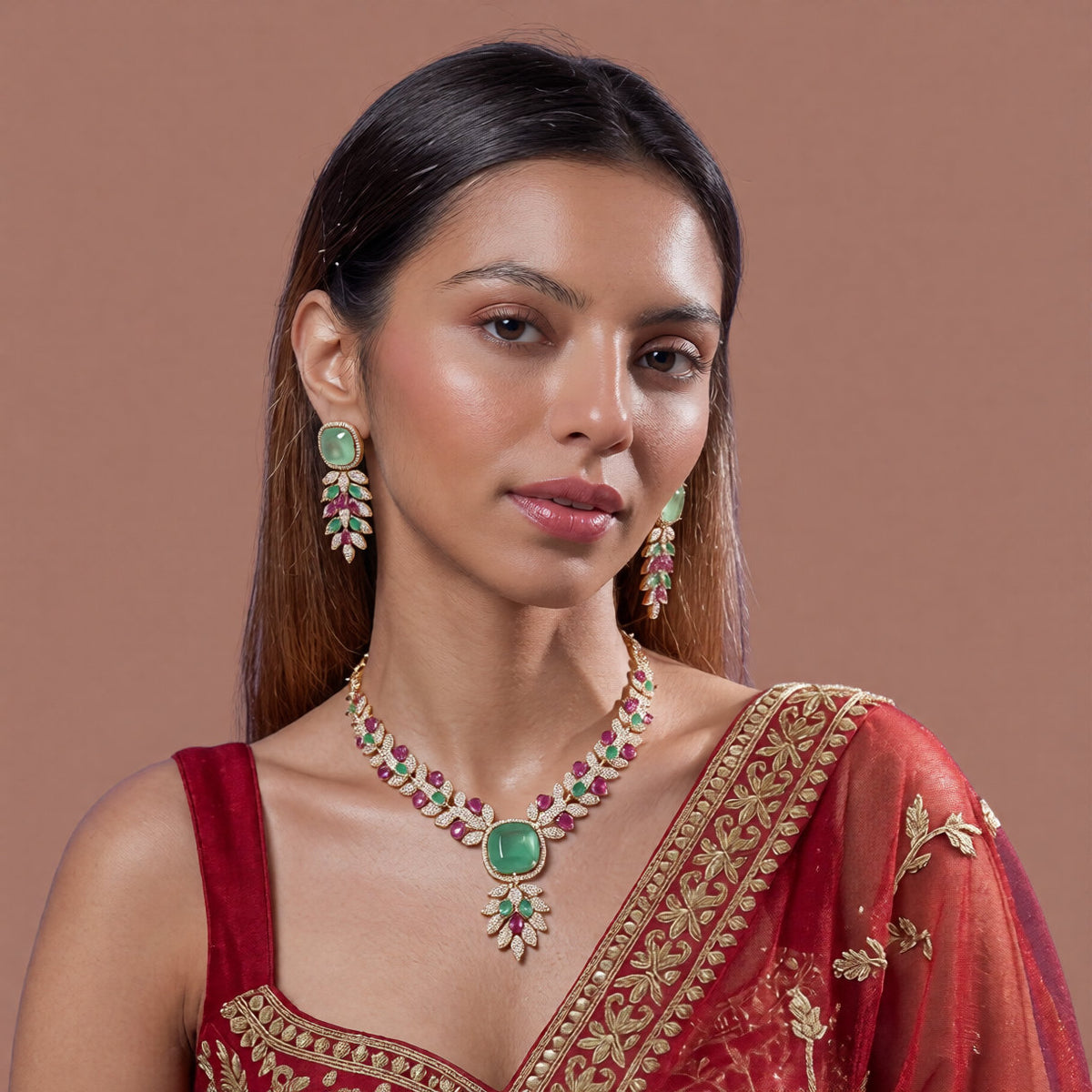 Rose gold American diamond leaf-vine necklace set with a mint-green square centre stone, ruby-pink accents and matching leaf-drop earrings on a grey display bust