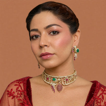 Gold-tone American diamond rigid choker with bird motif, emerald-green stone, ruby-pink flowers and ruby cage drop with matching bird earring on a grey display bust