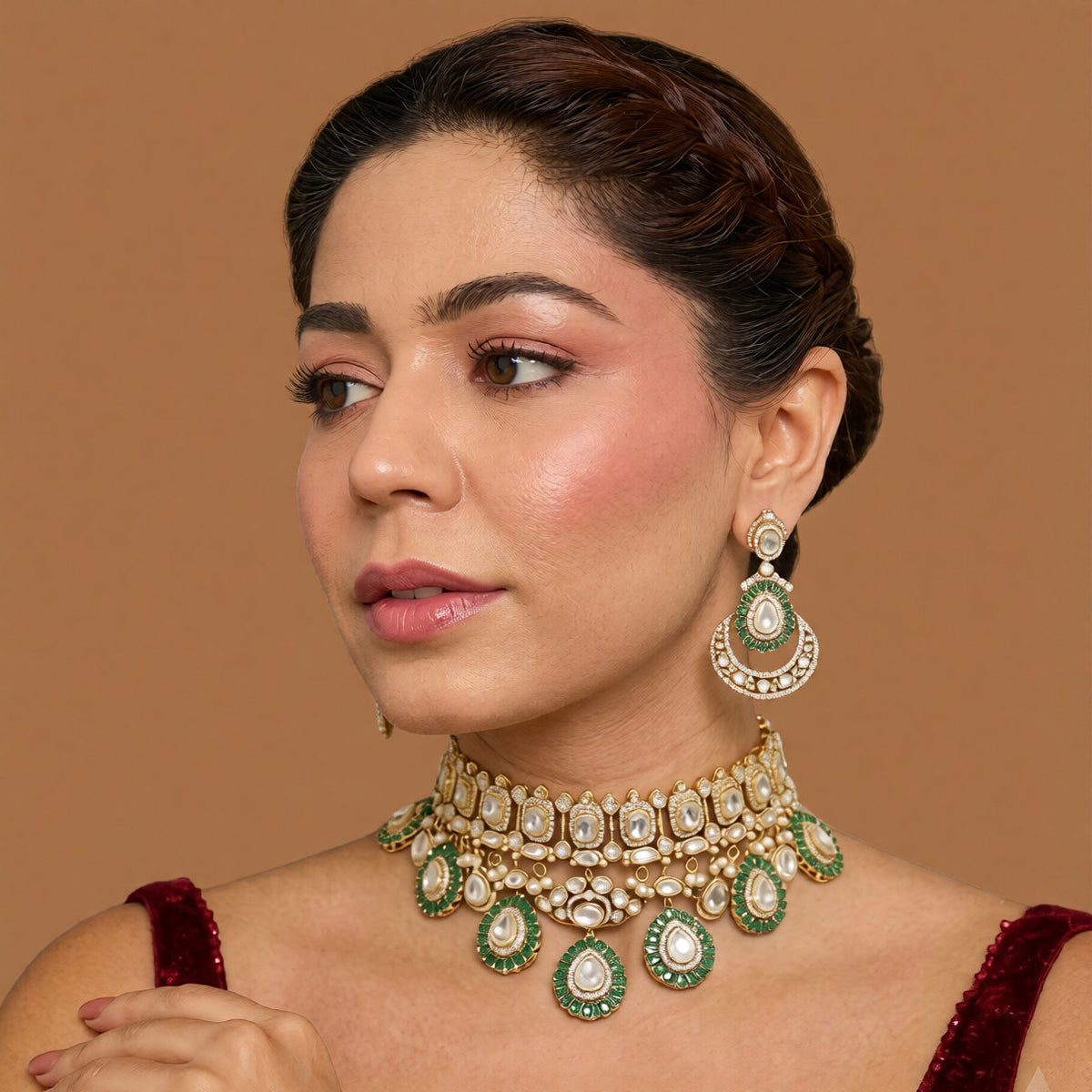 Gold Victorian kundan bridal choker with emerald-green ringed pear drops and matching crescent chandelier earrings on dark green velvet