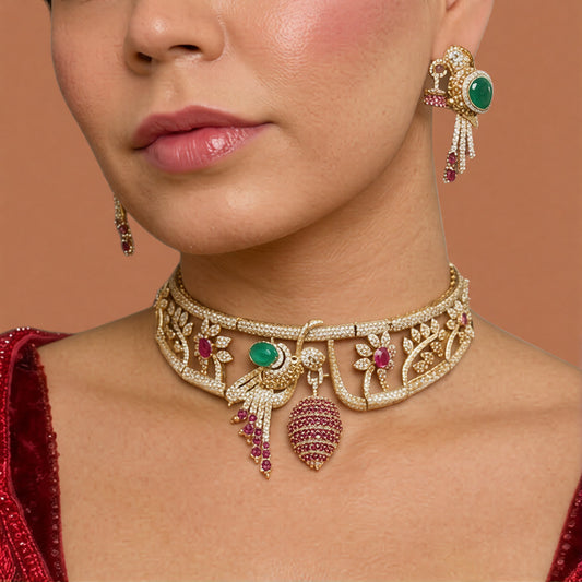 Gold-tone American diamond rigid choker with bird motif, emerald-green stone, ruby-pink flowers and ruby cage drop with matching bird earring on a grey display bust