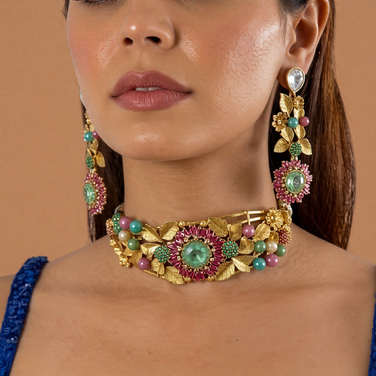Antique gold rigid choker with leaf and flower design, ruby-pink baguette flower, mint-green centre stone and multicolour beads with matching drop earring on a grey display bust