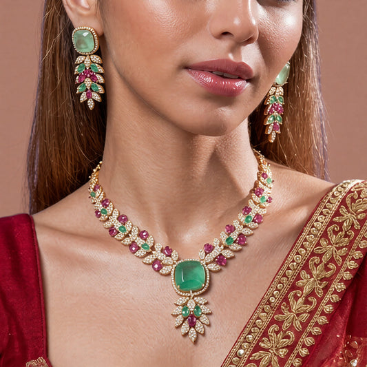 Rose gold American diamond leaf-vine necklace set with a mint-green square centre stone, ruby-pink accents and matching leaf-drop earrings on a grey display bust