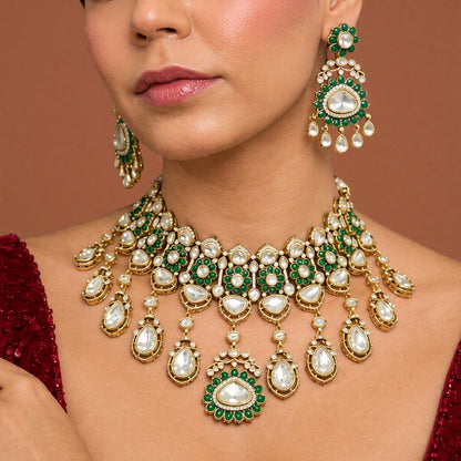 Antique gold Victorian kundan bridal choker with emerald-green flower medallions, pear-stone drops and a matching drop earring on a grey display bust