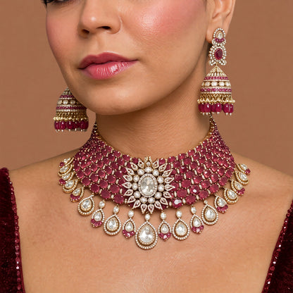 Antique gold Victorian bridal choker set with ruby-red oval stones, kundan floral centre and pear drops with matching ruby jhumka earrings on a white background