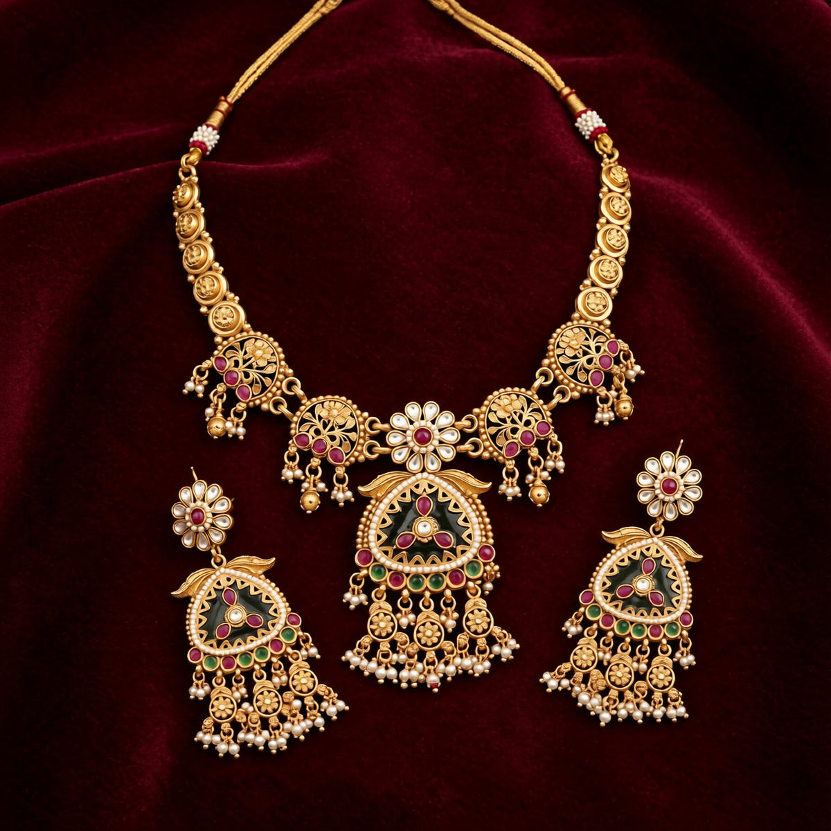 Antique matte gold temple necklace set with green triangular pendant, ruby pink stones, pearl drops and matching chandelier earrings on teal bust