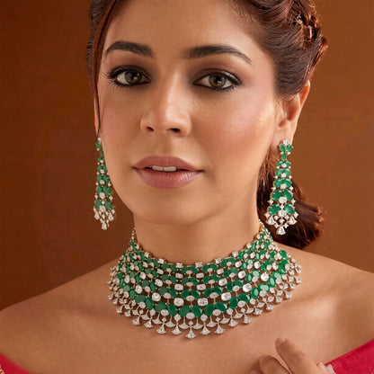 Emerald green American diamond choker necklace on a display bust with a matching long drop earring in hand