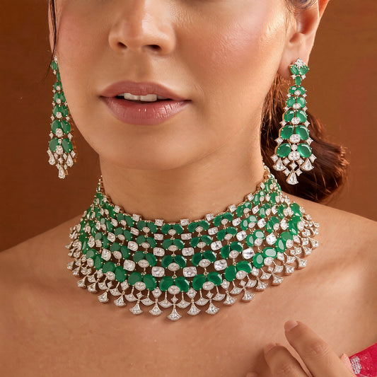 Emerald green American diamond choker necklace on a display bust with a matching long drop earring in hand