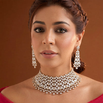 Gold finish American diamond bridal choker necklace on a display bust with a matching long drop earring in hand