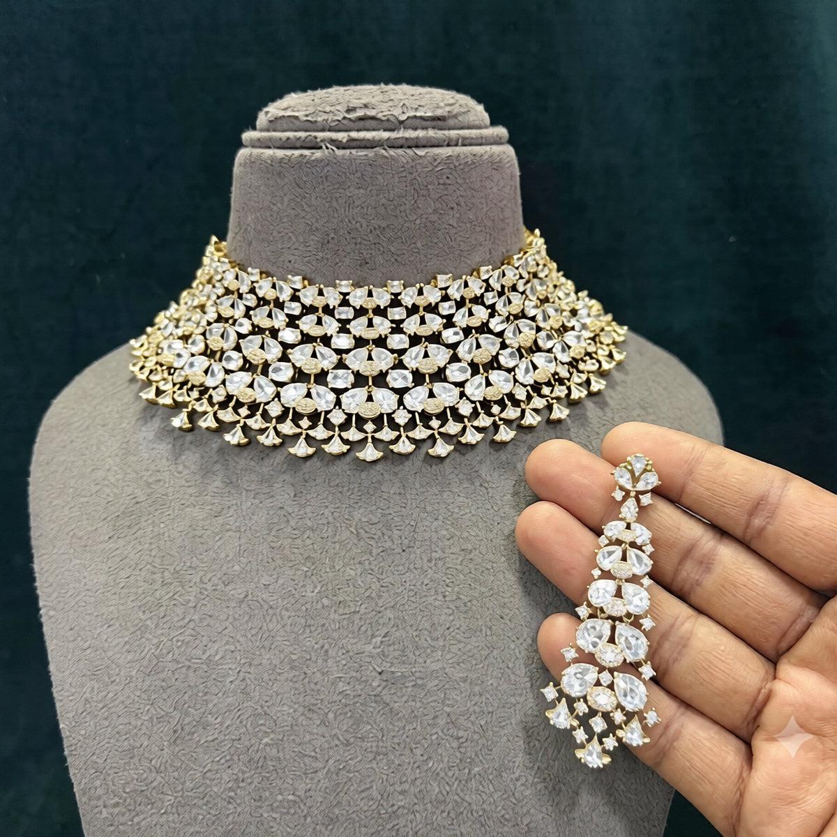 Gold finish American diamond bridal choker necklace on a display bust with a matching long drop earring in hand