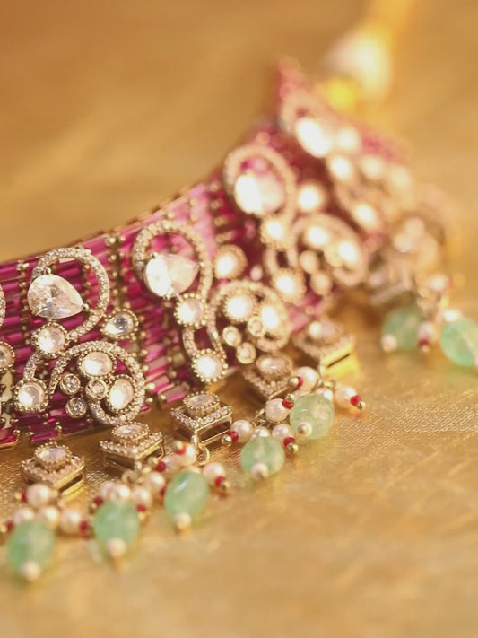 Kundan bridal necklace set with pink stones, green bead drops, and matching statement earrings in gold tone
