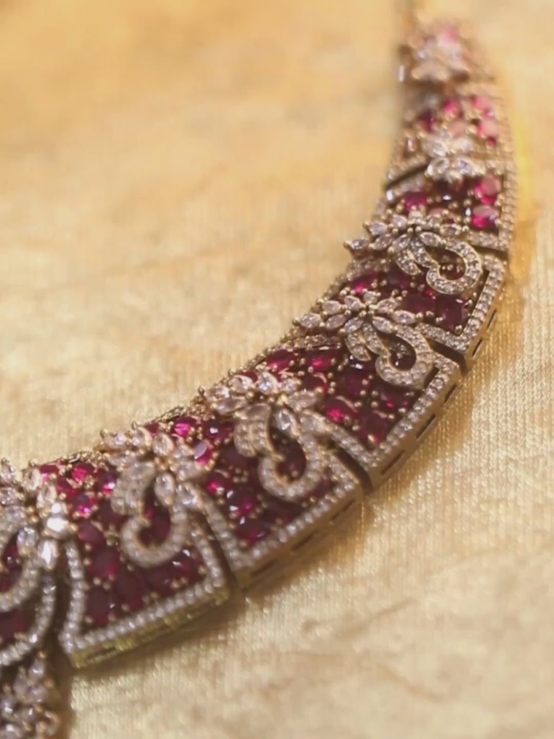 Gold-tone statement necklace set with pink ruby-style stones and clear crystals in an intricate floral design, paired with matching chandelier earrings featuring drop accents.