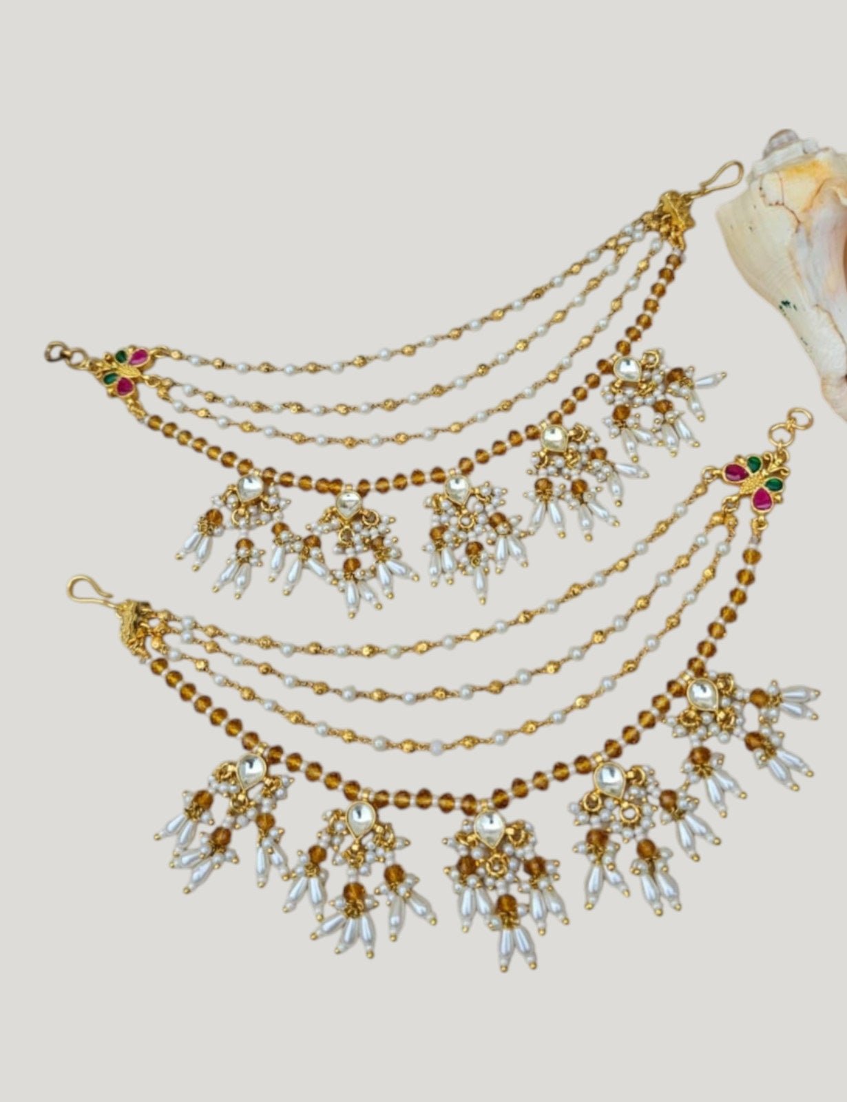 Traditional Kundan & Pearl Multi - Layer Kaan Chain - Auraa Trends - Kaan chain -  - Auraa Trends - Elegant multi - layered Kundan and pearl golden Kaan Chain (Ear Chain) with floral motifs and dangling pearl drops, displayed with decorative flowers and seashell.